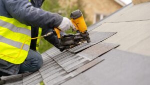 A roofer installing asphalt shingles