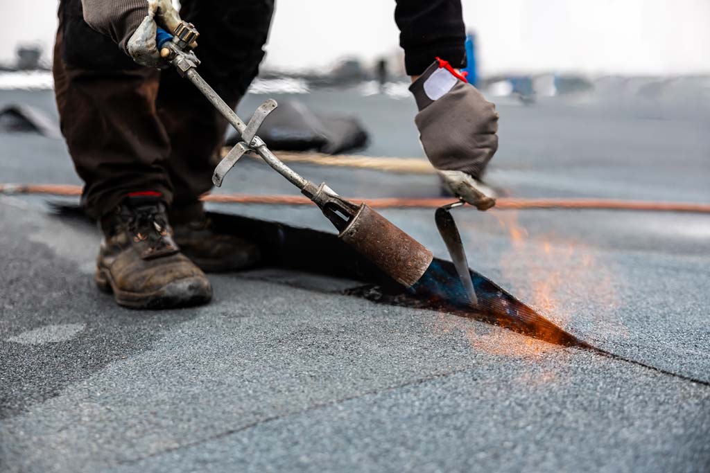 A roofer installing a bitumen roof with heat 