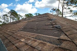 A storm damaged roof with underlayment exposed